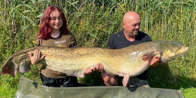 Hannah Truscott (left) and her dad Paul Truscott (right) hold up her 96-pound, 4-ounce catch. The 15-year-old reportedly caught the giant catfish at the White Lakes in Essex County.