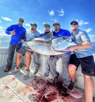 A crew of five hold up a large bigeye tuna.